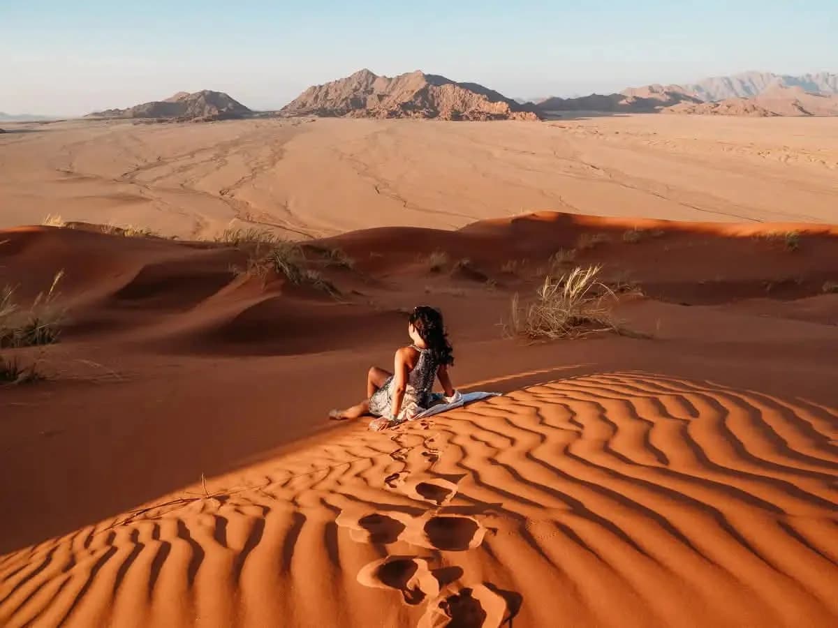 Woman sitting on a Namib dune