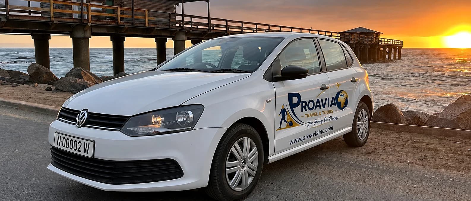 White ProAvia-branded Volkswagen Polo parked at a Namibian coastal pier at sunset